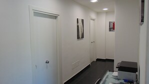 A hallway with white walls, a black-tiled floor, and a glass table with a map and office supplies. - B&B Etna's Tourist (Catania)