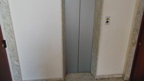 A narrow elevator with a metallic interior, white walls, and a marble floor. - B&B Etna's Tourist (Catania)