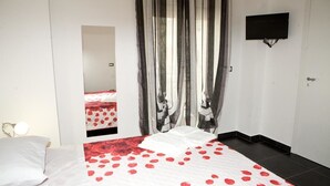 A hotel room with a bed, a TV mounted on the wall, and a mirror reflecting the room. - B&B Etna's Tourist (Catania)