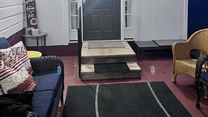 A living room with a blue door, white walls, a dark rug, and a wicker chair. - Warm Springs Retreat (Warm Springs)