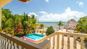 A balcony with a pool, tropical plants, and a view of the ocean. - Beachfront Villa • Private Pool • Fully Fenced • Walk to Restaurants (Placencia)