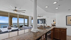 A modern kitchen with granite countertops, a built-in dishwasher, and a view of the ocean.