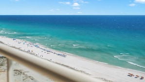 A beach with clear turquoise waters, a sandy shore, and a row of blue umbrellas.