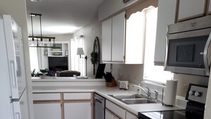 Eine moderne Küche mit weißen Schränken, einem Edelstahlkühlschrank, einer Mikrowelle und einem eingebauten Backofen.