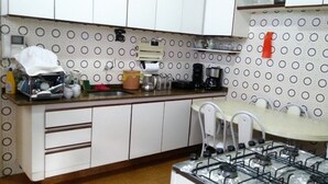 A compact kitchen with a gas stove, white cabinets, and a patterned backsplash. - Casa Maceio Shopping (Maceió)