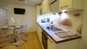 A modern kitchen with a glass dining table, stainless steel appliances, and a flat-screen TV mounted on the wall. - 29 - Livingtarifa Ventura Levante (Tarifa)