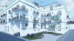 A multi-story building with balconies, a car parked in front, and a small garden area with benches. - 29 - Livingtarifa Ventura Levante (Tarifa)