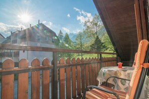 Enjoy a peaceful view from this balcony with a table and chair.