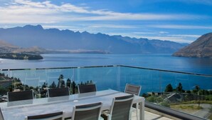 A dining area with a glass balustrade overlooking a lake and mountains. - 7Manata - Amazing 270deg views! Golf & Ski 10bedrm/8bathrm + 4x seven-seat 4WD's (Fernhill)