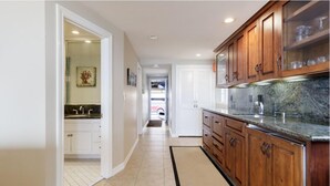 A kitchen with wooden cabinets, a granite countertop, and a tiled floor. - Seaside Home - Full home rental - Beachfront, Full Beach Front Home - 2002 W. Oceanfront (Newport Beach)