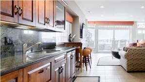 A modern kitchen with wooden cabinets, a stainless steel sink, and a large window overlooking a balcony. - Seaside Home - Full home rental - Beachfront, Full Beach Front Home - 2002 W. Oceanfront (Newport Beach)