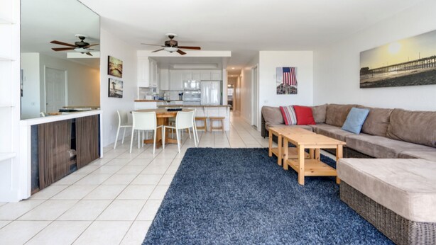 A modern living room with a sofa, a coffee table, and a dining area with chairs and a table.