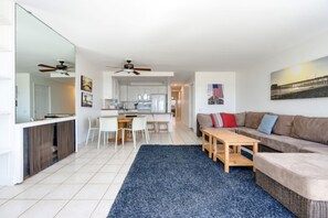 A modern living room with a sofa, a coffee table, and a dining area with chairs and a table. - Beachfront Condo - 2nd Floor - "Beatrice" (Newport Beach)