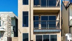 A modern multi-story building with a flat roof, large windows, and a stone facade.