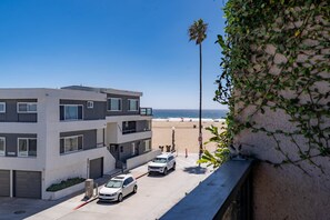 A multi-story building with a parking area and a view of the beach. - Oceanview Condo - 3rd floor - "Daniel" (Newport Beach)