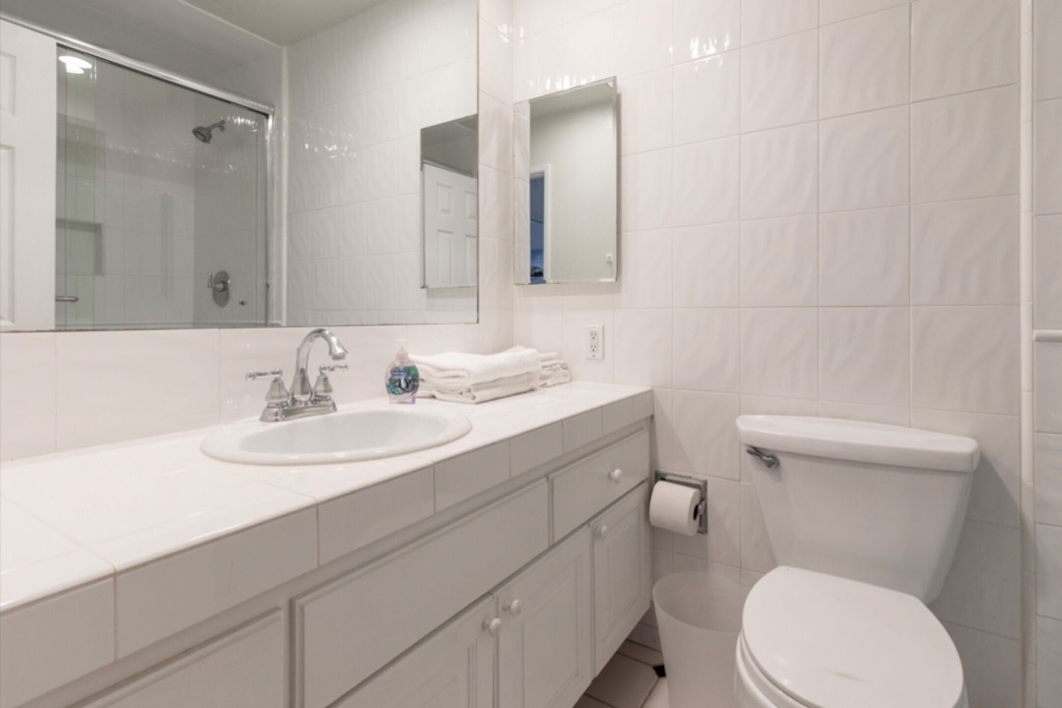 A modern bathroom with a white sink, mirror, and toilet.