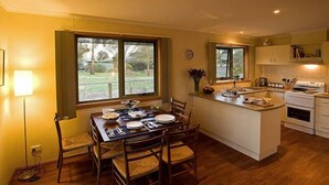 Een moderne keuken met een eethoek, grote ramen en uitzicht op de omgeving.