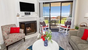 Un salón con chimenea, un televisor de pantalla plana y vistas al océano.