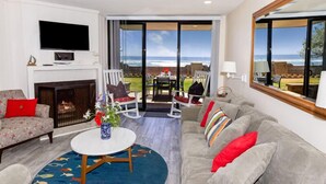 Una sala de estar con chimenea, televisor y vista al océano.