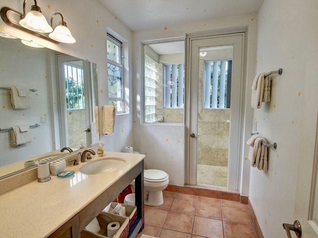A bathroom with a sink, mirror, towel rack, toilet, and shower area.