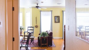A hallway with wooden flooring, a ceiling fan, and a dining area with a table and chairs. - High Cotton Inn (New Braunfels)