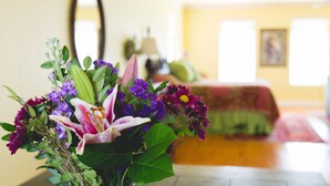 A room with a bed, a mirror, and a floral arrangement on a table. - High Cotton Inn (New Braunfels)
