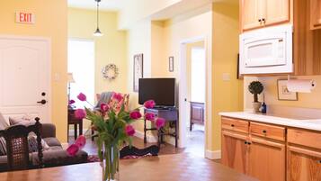 A kitchen with wooden cabinets, a microwave, and a dining table with a vase of flowers.