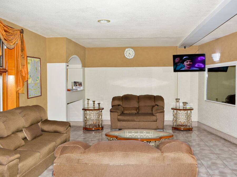 A living room with a brown sofa, a brown armchair, a glass coffee table, and two decorative side tables.