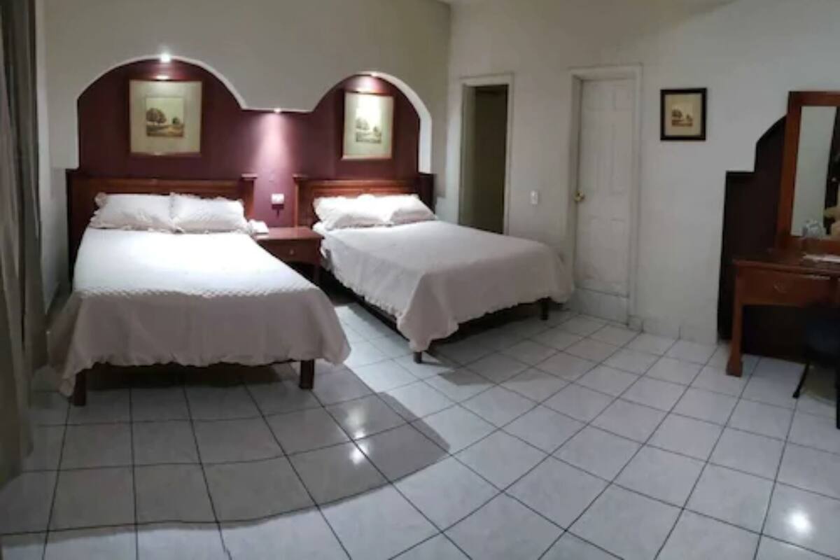 A hotel room with two beds, a desk, and a chair.