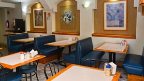 A restaurant interior with booths and tables, a fire extinguisher, and wall-mounted artwork. - Hotel Baeza (Delicias)