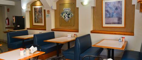 A restaurant interior with booths and tables, a fire extinguisher, and wall-mounted artwork.