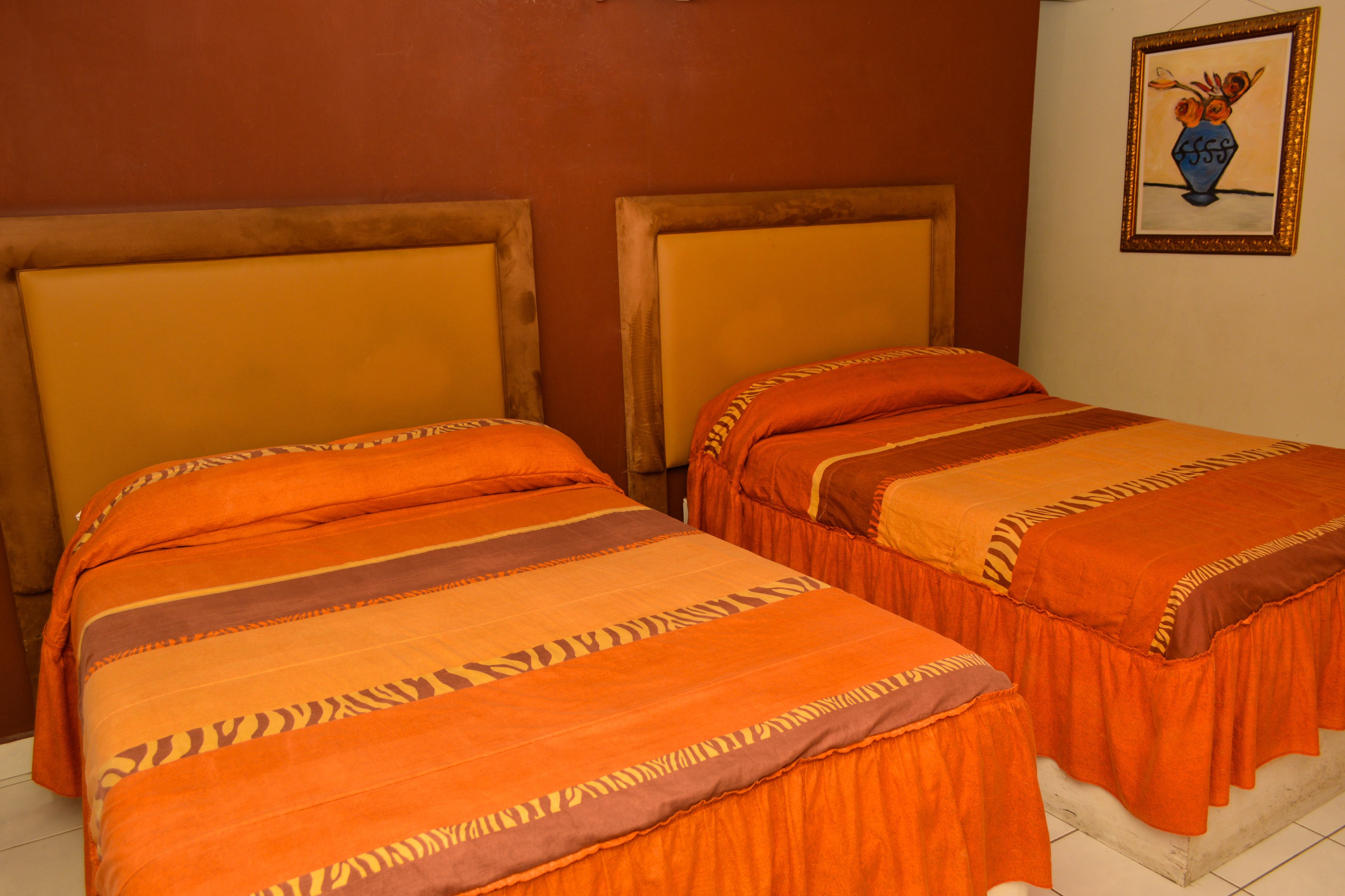Una habitación con dos camas, cada una con cabecero de madera y ropa de cama naranja.