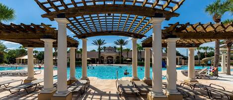 A pool area with a pergola structure, palm trees, and lounge chairs.