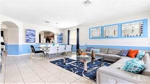 A modern living room with a dining area, featuring a sofa, coffee table, and a dining set.