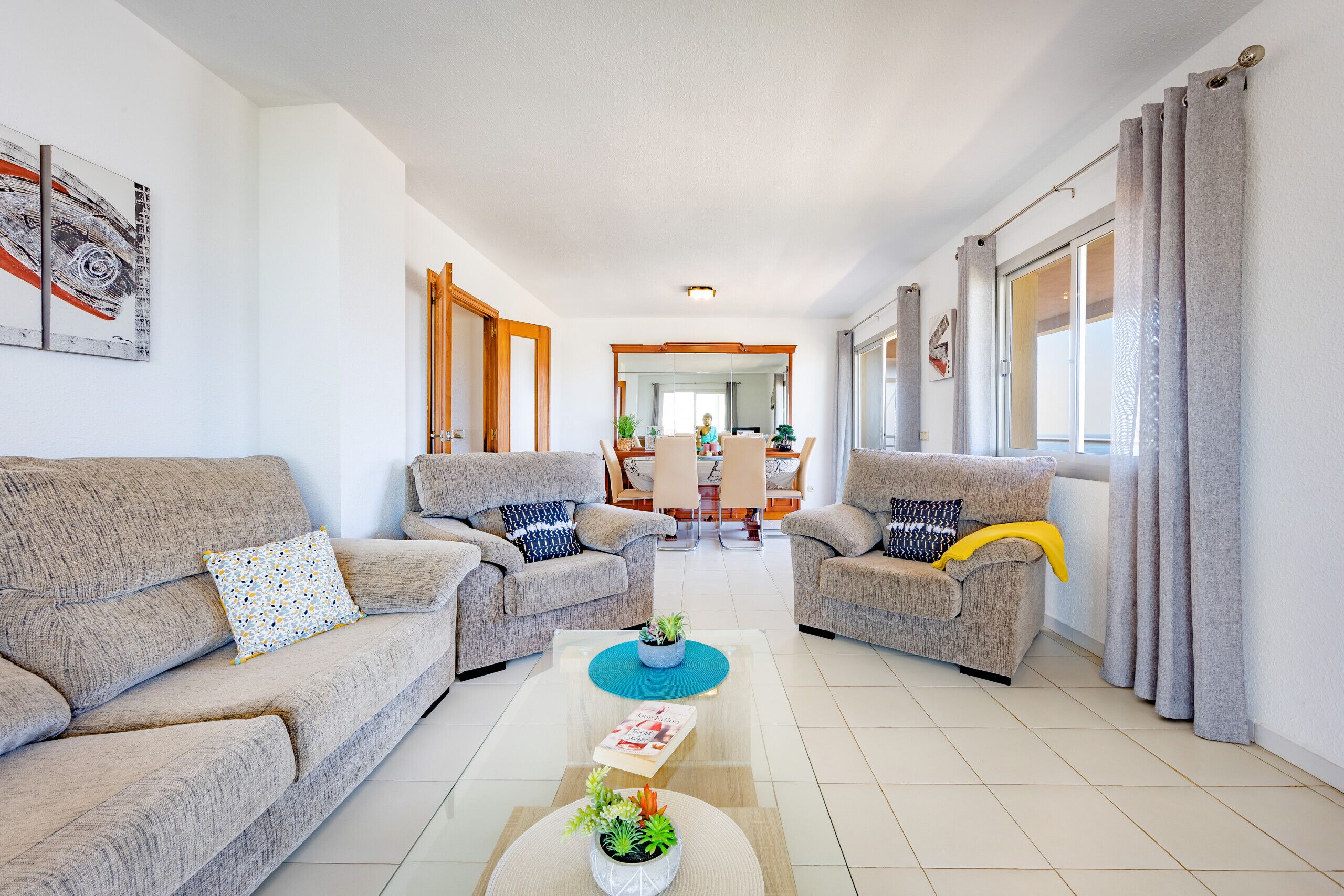 A modern living room with two sofas, a coffee table, and a dining area in the background.