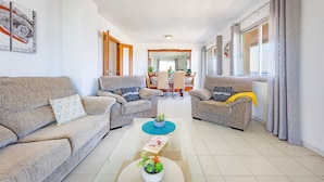 A modern living room with two sofas, a coffee table, and a dining area in the background. - Apartment Turmalina - PlusHolidays (Calpe)