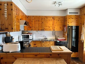 Uma cozinha moderna com armários de madeira, pia de aço inoxidável, micro-ondas, torradeira e geladeira.