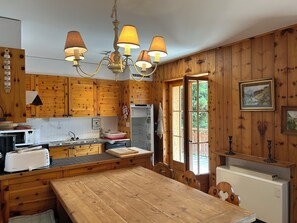 Cozinha de cabana de madeira com uma ilha central, uma mesa de jantar e uma janela grande.