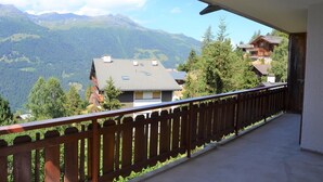 A balcony with a view of mountains and houses. - Outside : 3-room flat for 4 persons on the 1st floor, large terrace with garden furniture.Inside : e (St-Luc)