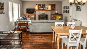 Een woonkamer met een bank, een salontafel, een eettafel met stoelen, een open haard en een televisie.