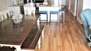 A modern kitchen with white cabinets, stainless steel appliances, and a wooden dining table with two bar stools.