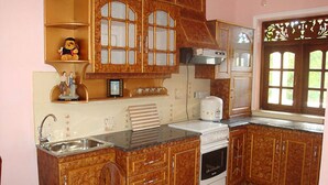 A kitchen with wooden cabinets, a stove, and a sink. - Mount House Hotel (Dikwella)