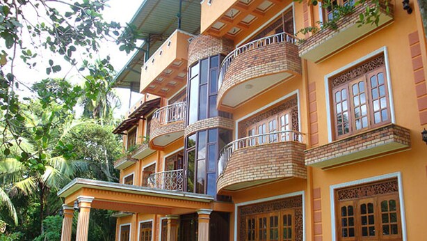 A multi-story building with a balcony on each floor, surrounded by greenery. - Mount House Hotel (Dikwella)