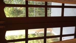 A view through a window with a wooden frame, revealing greenery outside. - Mount House Hotel (Dikwella)