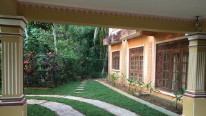 A courtyard with a paved pathway, lush greenery, and traditional architectural elements. - Mount House Hotel (Dikwella)