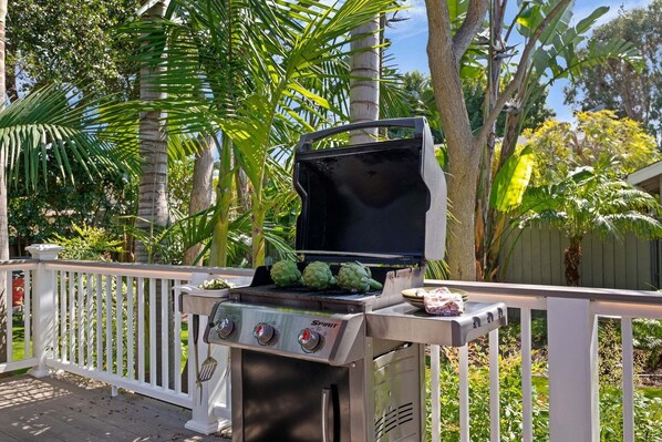 A barbecue grill with artichokes on it, surrounded by a white fence and lush greenery. - Charming Home w/ Private, Enclosed Yard, Easily Accessible to All of SB! (Santa Barbara)