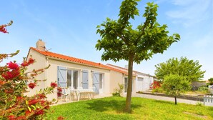Ein zweistöckiges Haus mit rotem Ziegeldach, einem kleinen Garten und einem weißen Zaun.