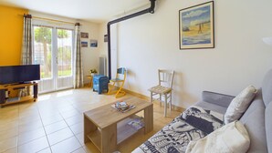 Ein Wohnzimmer mit einer Couch, einem Couchtisch, einem Fernseher und einem Bild an der Wand.
