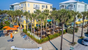 Un hotel sul lungomare con posti a sedere all'aperto, palme e vista libera sull'oceano.