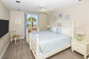 A bedroom with a bed, a chair, a nightstand, and a ceiling fan. - Beachfront lower cottage, panoramic view, D31 North Coast Village (Oceanside)